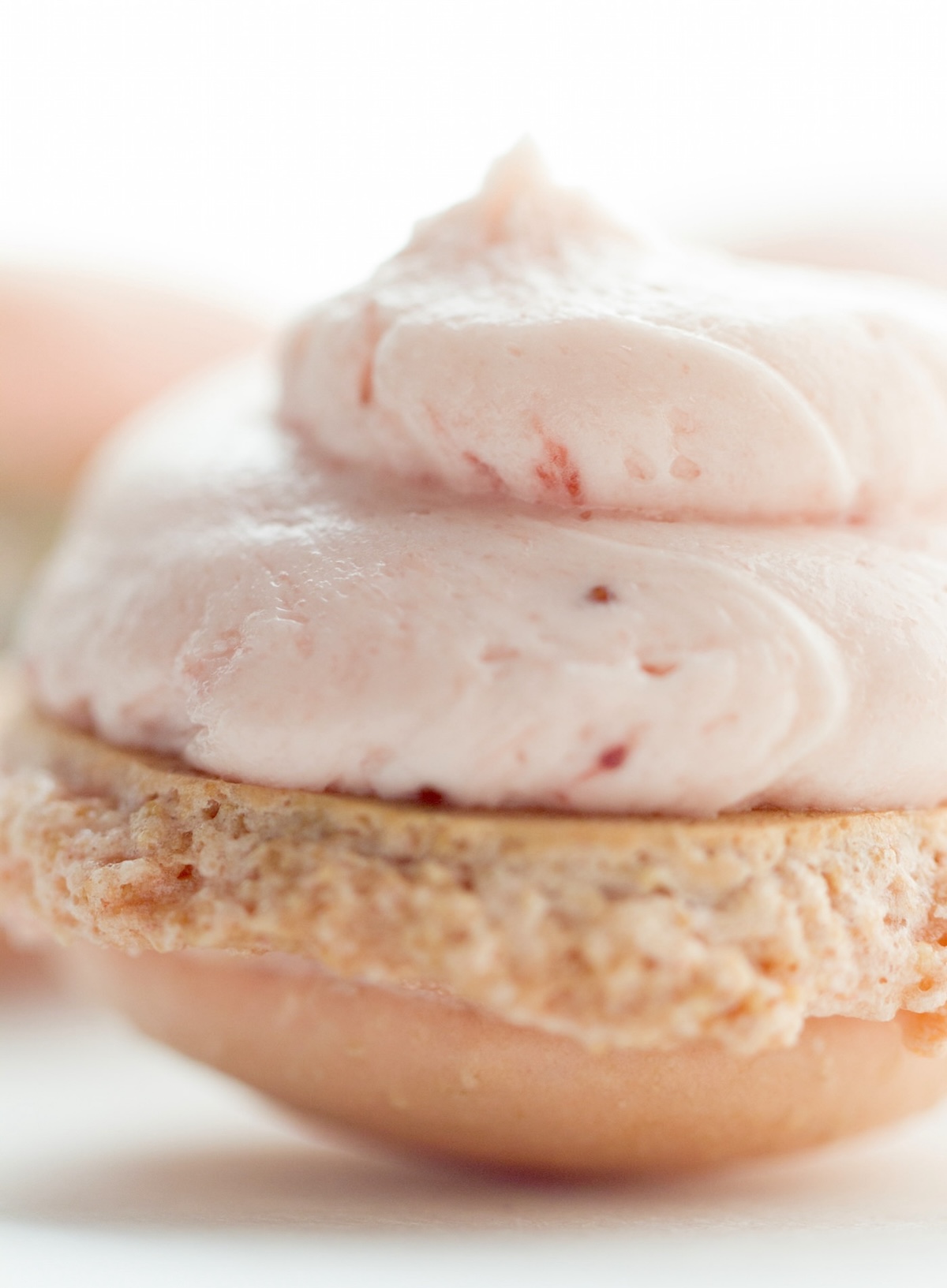 Close up of filling on top of a strawberry macaron