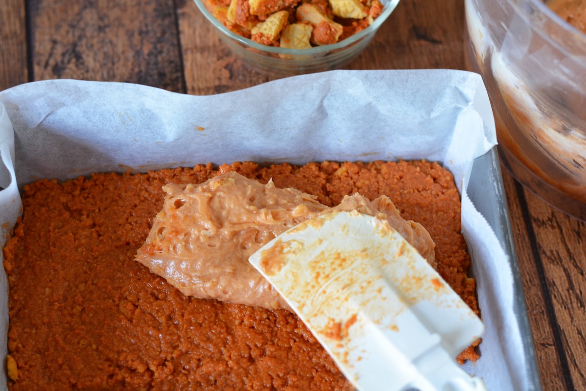 Pumpkin filling being spread over the crust with a spatula