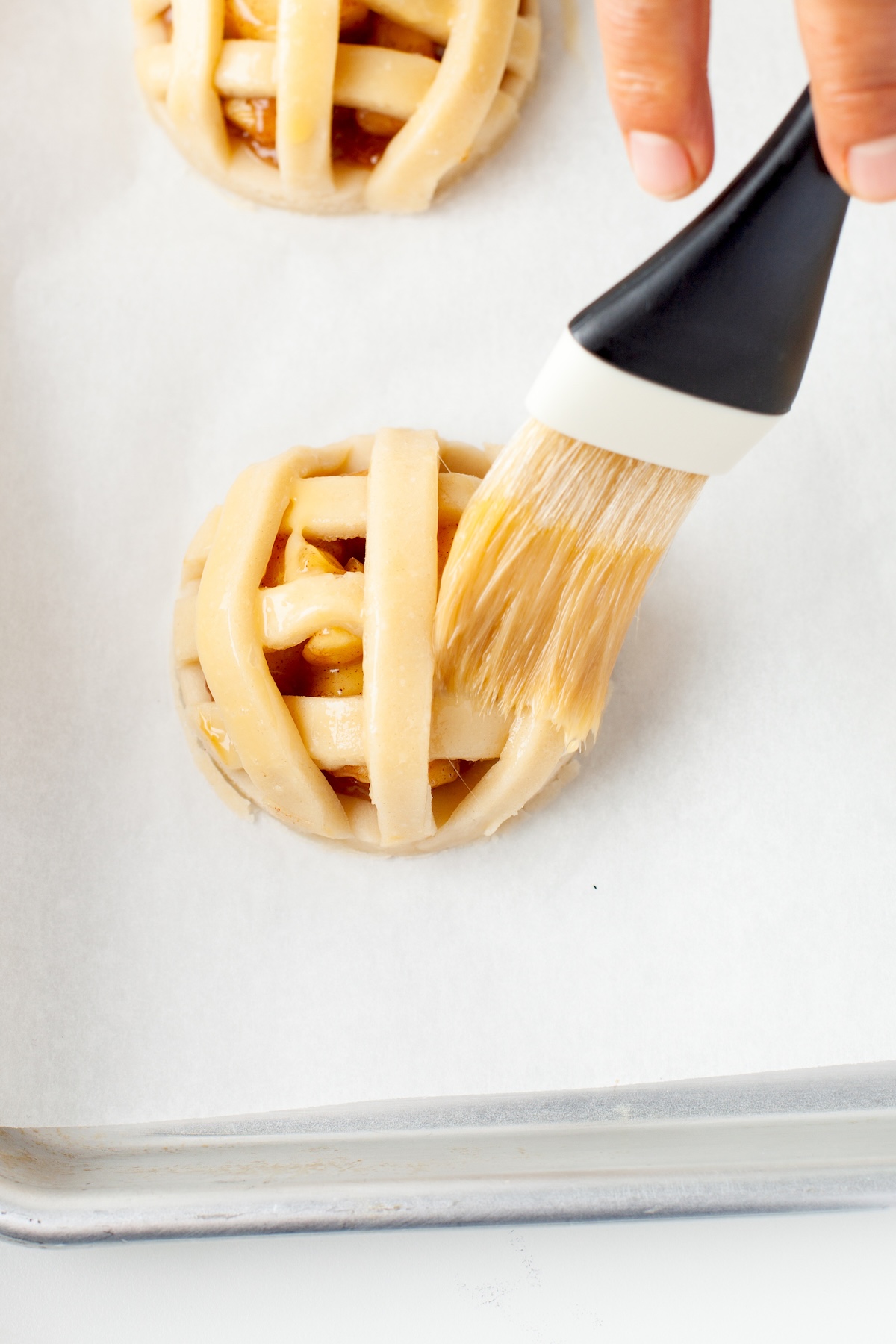 Brushing egg wash on top of the mini pie cookies