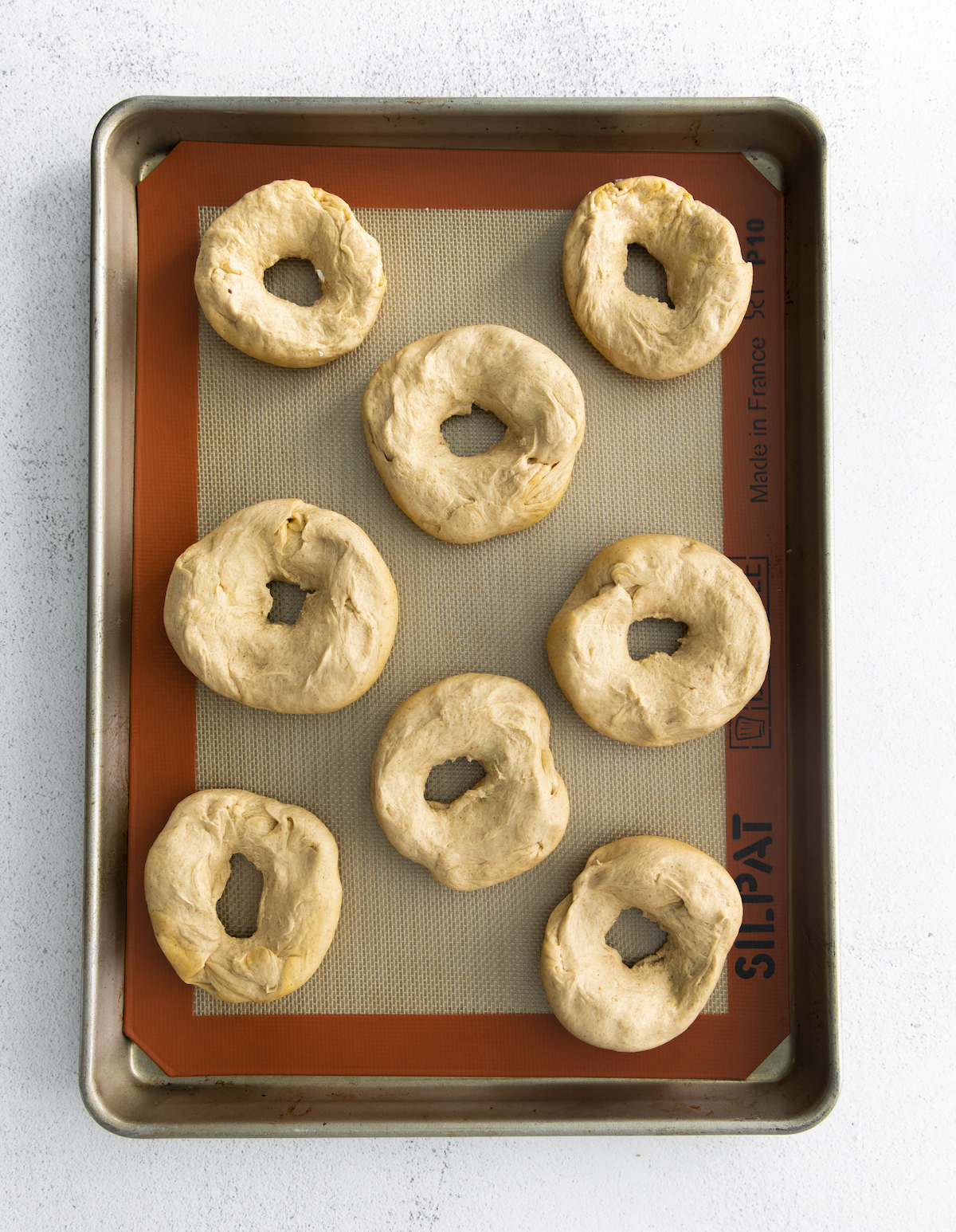 Holes poked in the middle of the bagel dough