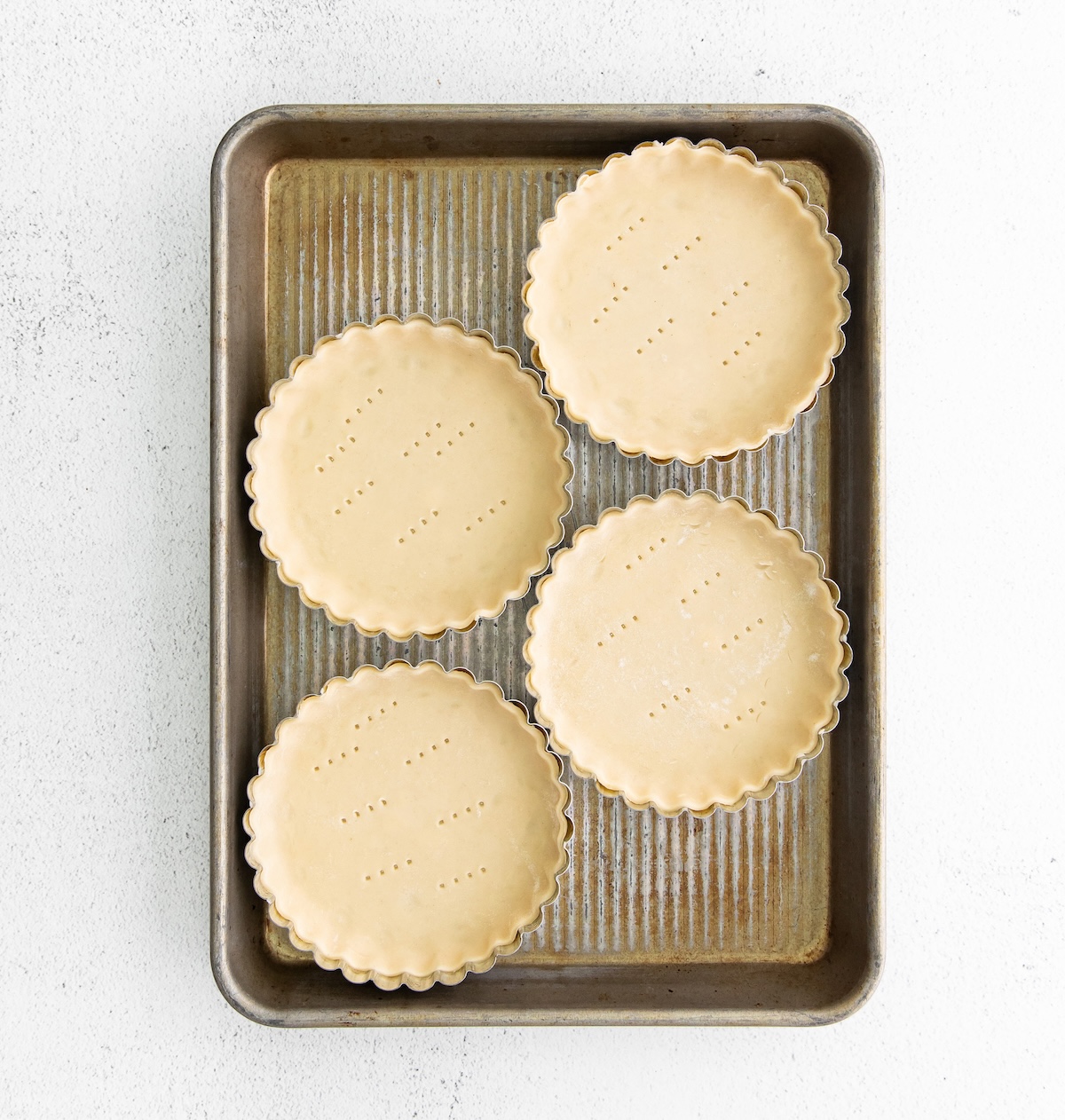 Dough pressed into tart pans with fork marks