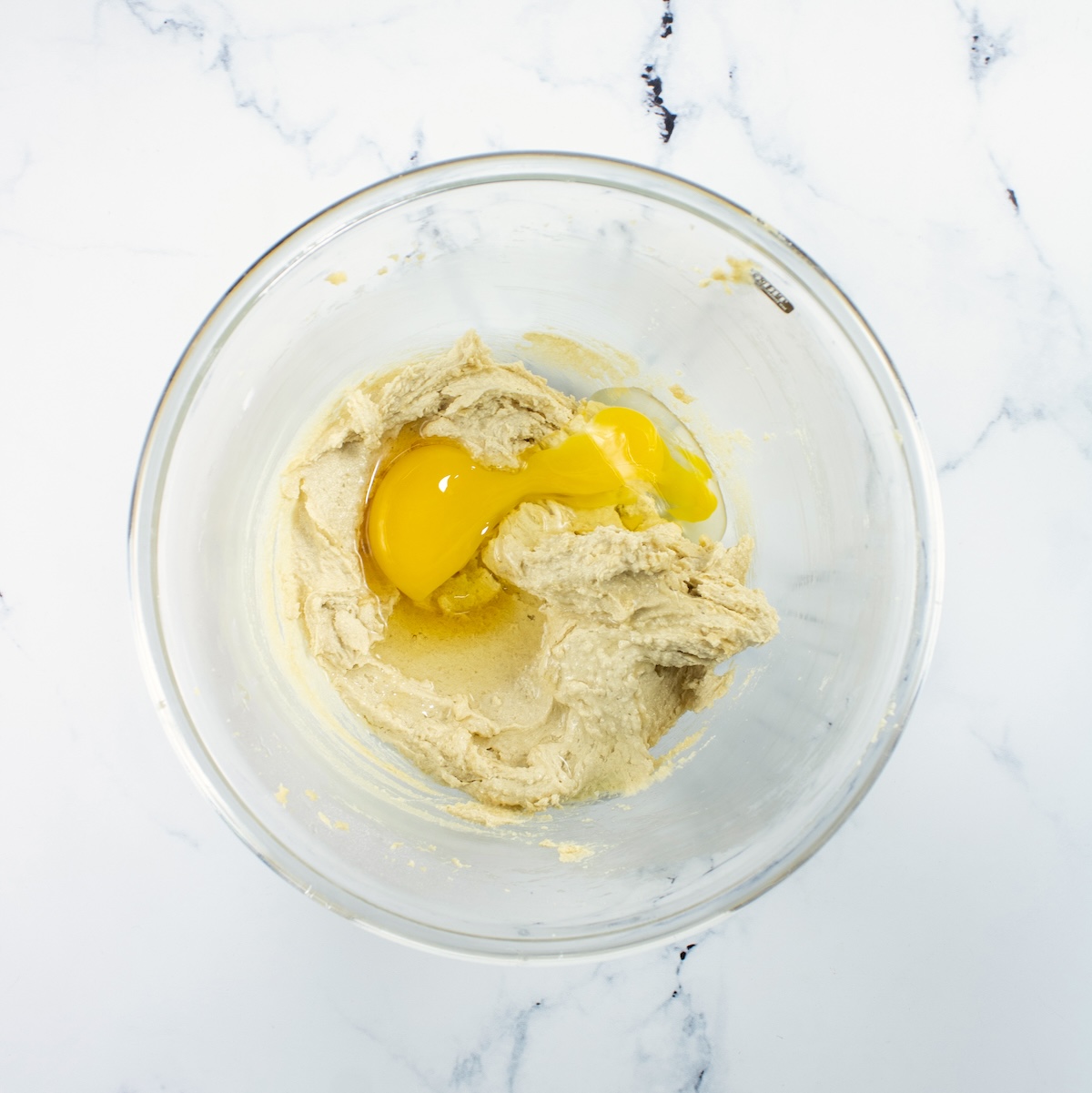 Egg and vanilla added to the cookie batter in a clear glass bowl