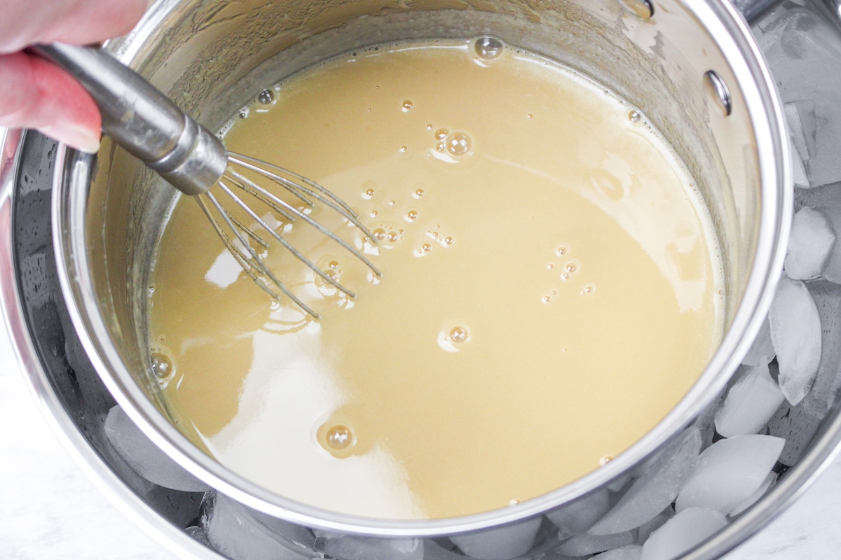 Metal bowl set into ice with a hand stirring