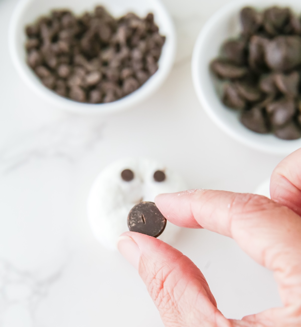 Placing two chocolate chips for the eyes