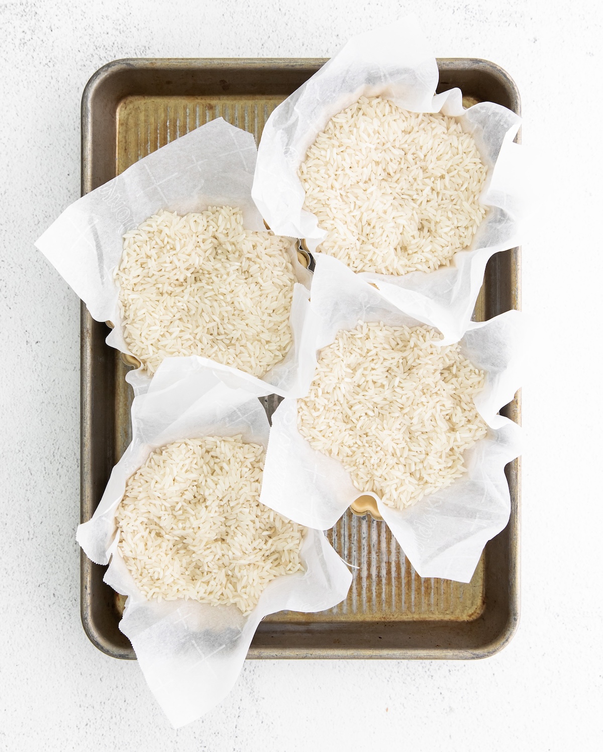 Tart crusts filled with rice on a baking sheet