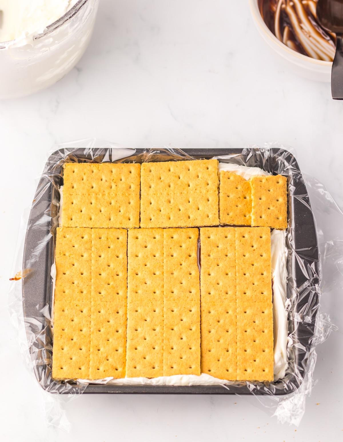 Topping the fudge and marshmallow with graham crackers
