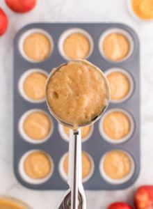 spooning the apple cider batter into the muffin tin