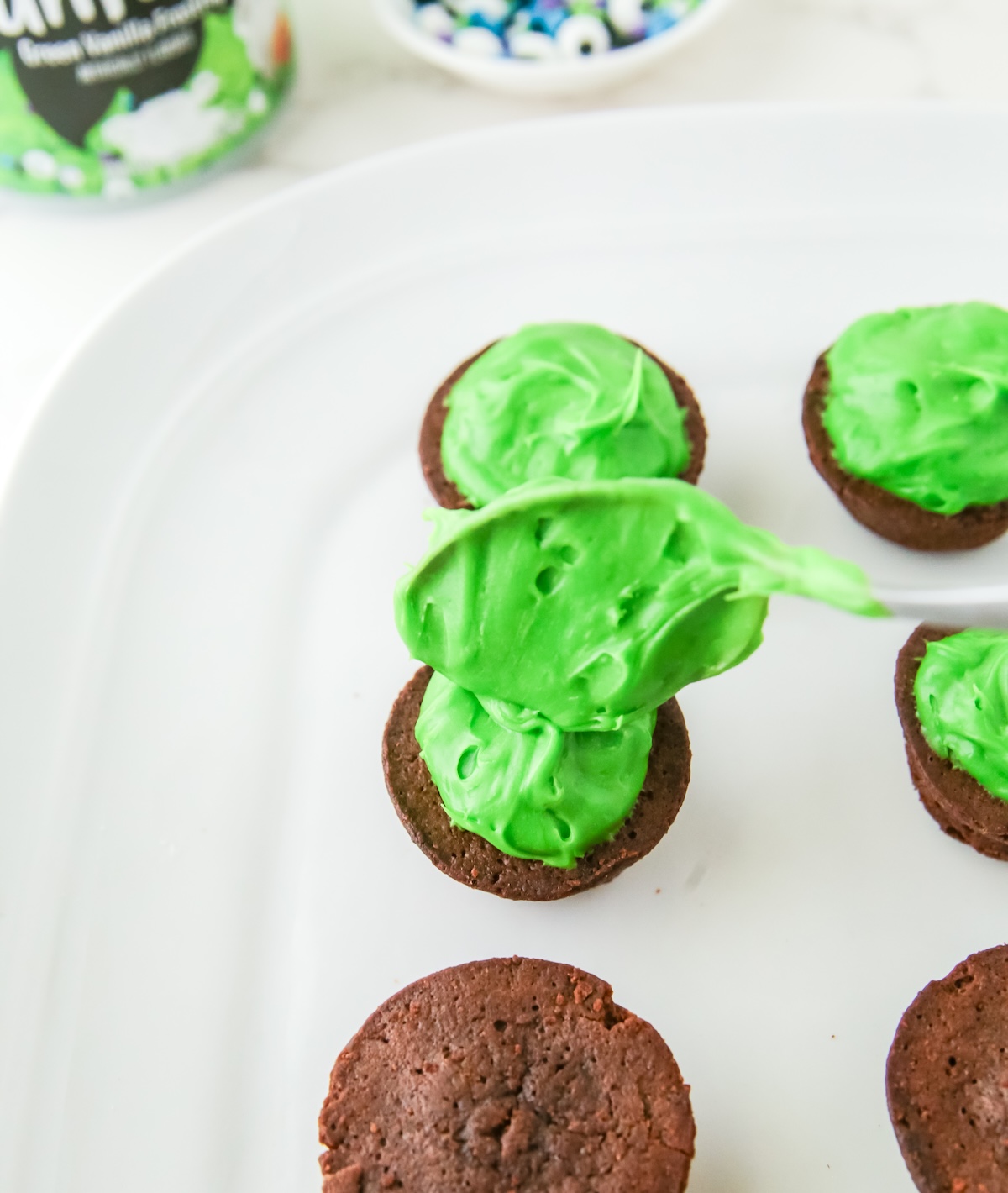 Adding green frosting to the brownie bites