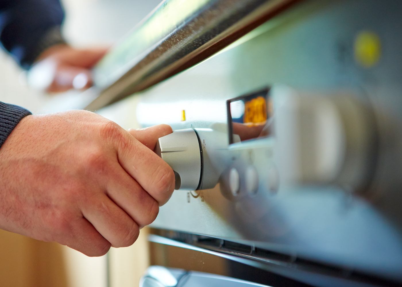 hand turning an oven on