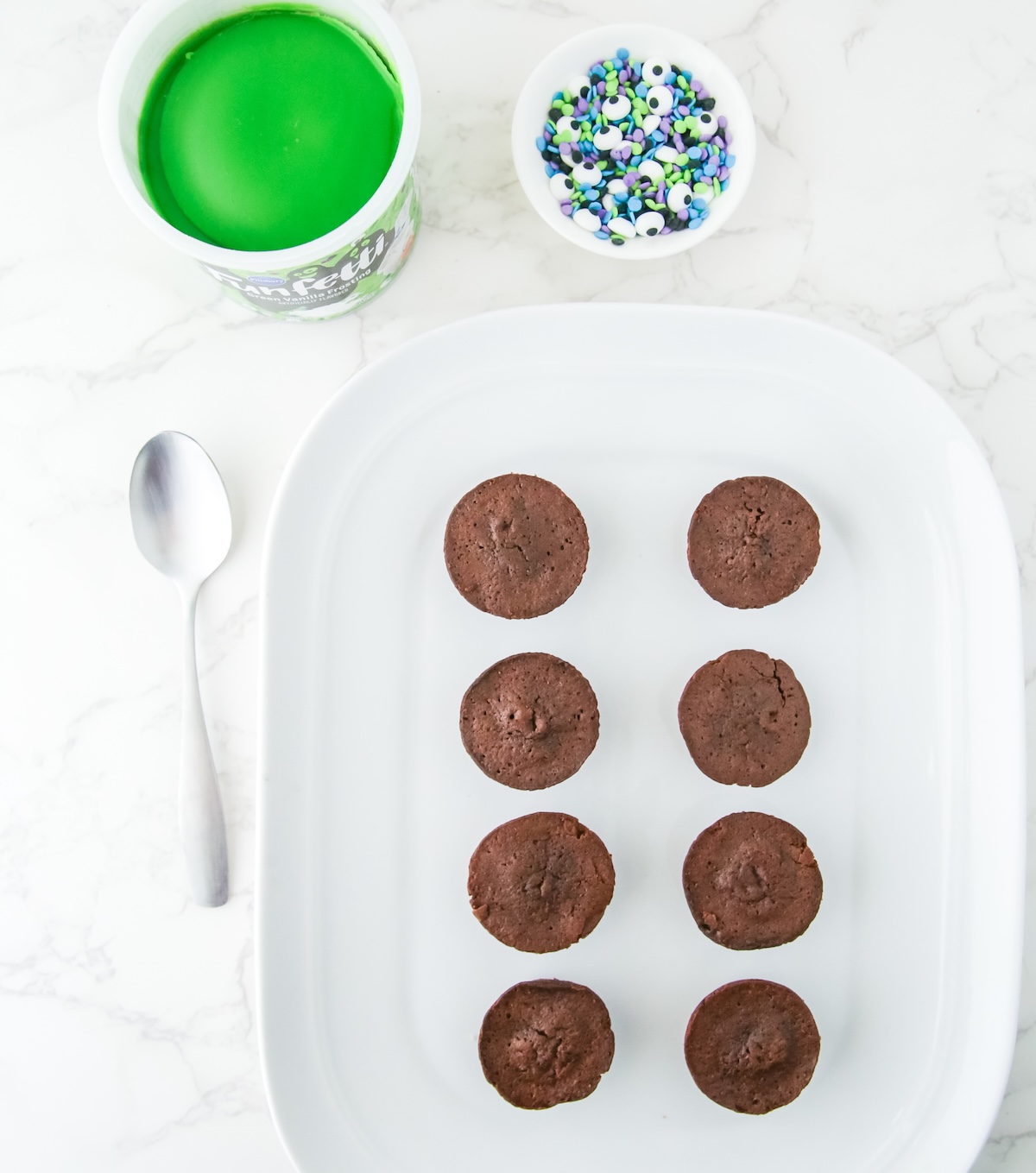 Frosting, sprinkles, and brownies on a plate