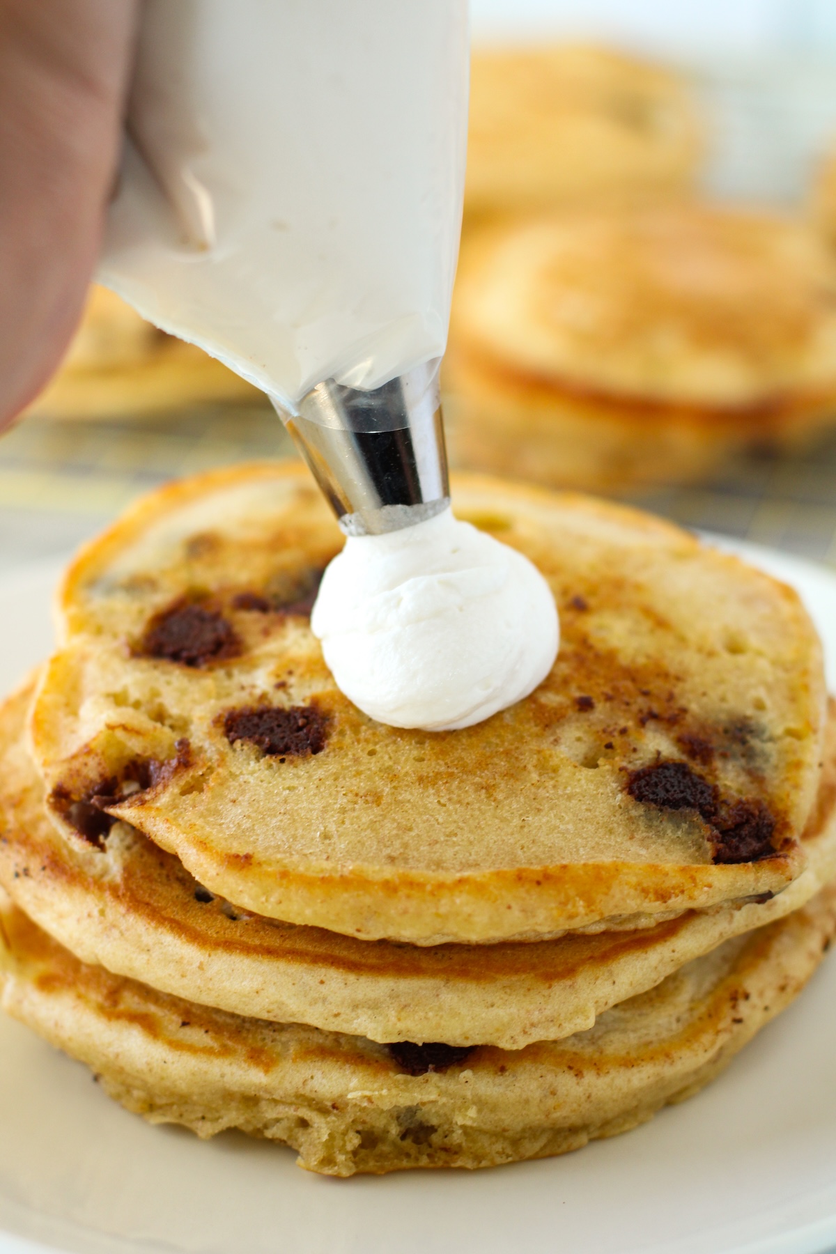 Piping whipped cream onto the pancakes