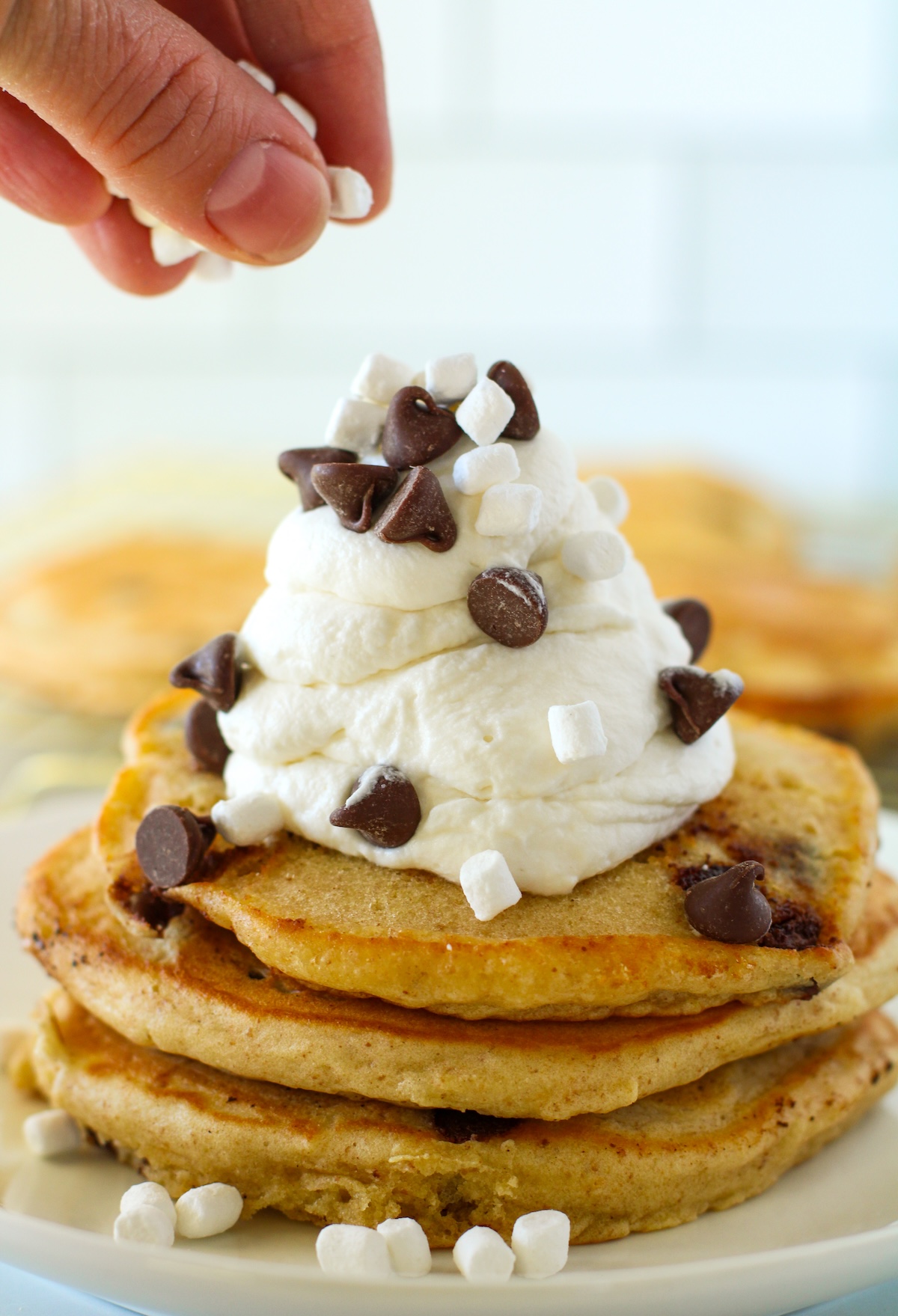 Sprinkling marshmallows and chocolate chips on the pancakes