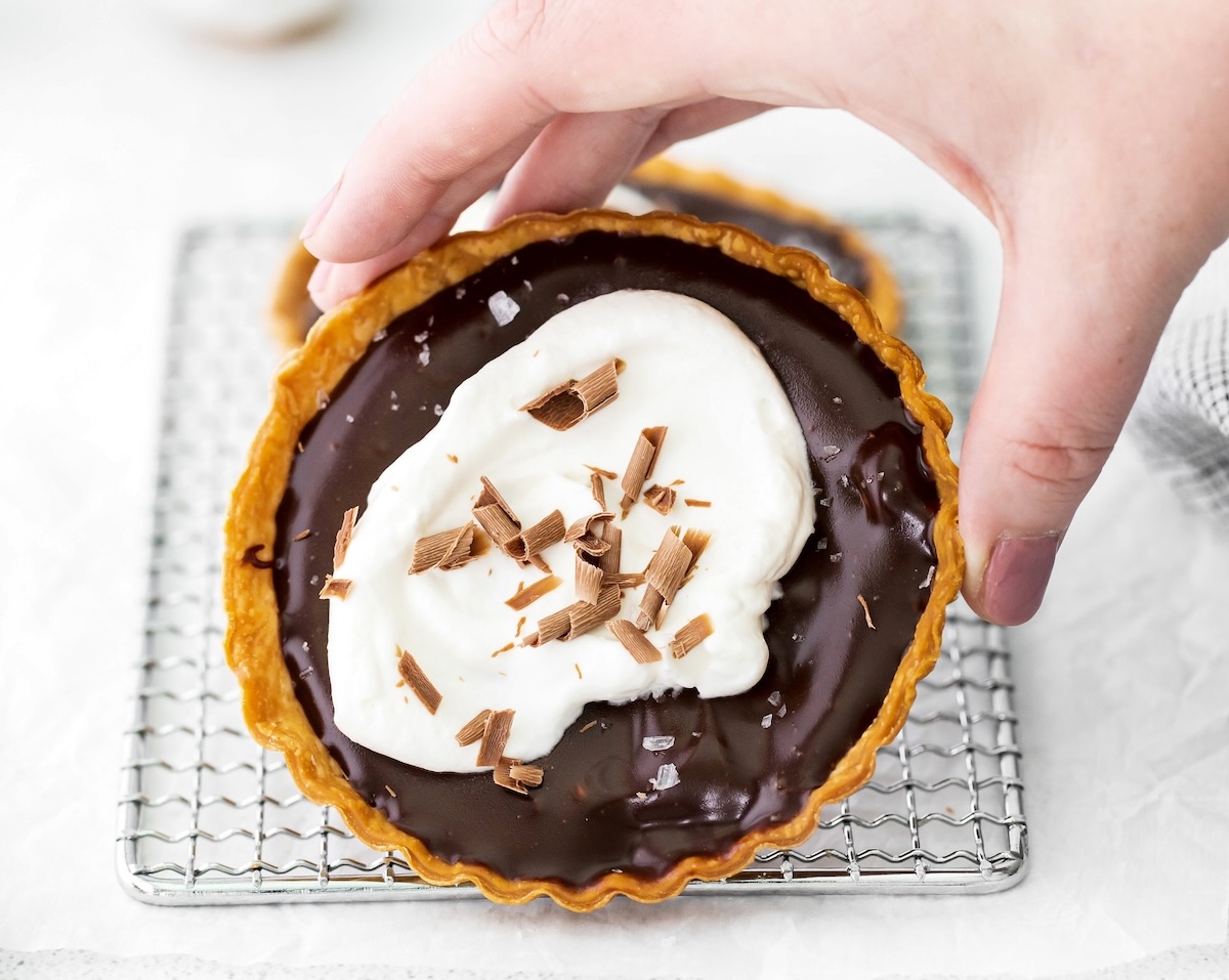 woman's hand holding a homemade chocolate tart