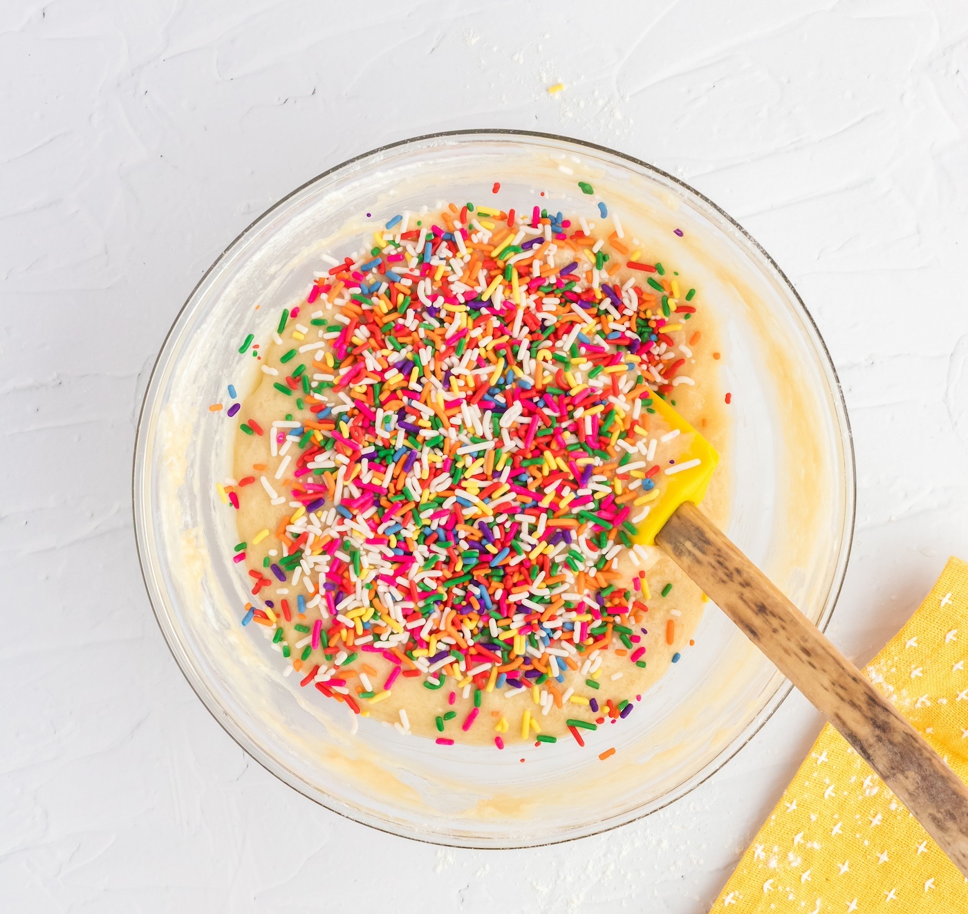 folding rainbow sprinkles into the batter